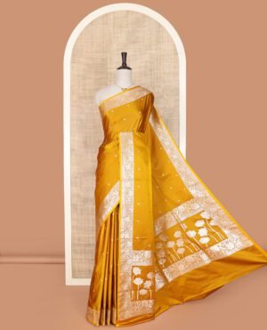 Yellow Semi-Banaras Satin Saree Subtly Sparkled With Zari Buttas, Self-Border Gleamed Up With Floral Creeper Designs, Pallu Creatively Woven Of Lotus Motifs, And Paired With A Matching Blouse