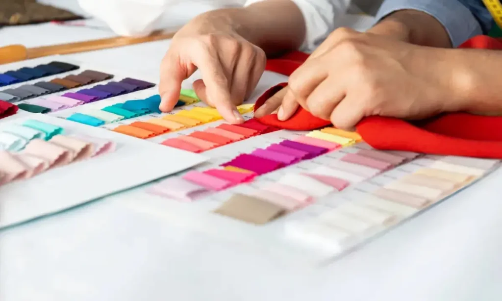 Two people comparing fabric colors using a swatch chart.