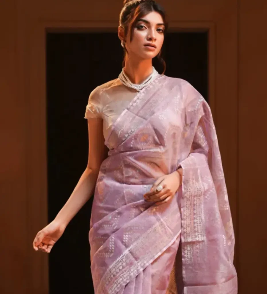 Woman in elegant lilac silk saree and pearl necklace posing for cultural wellness campaign.