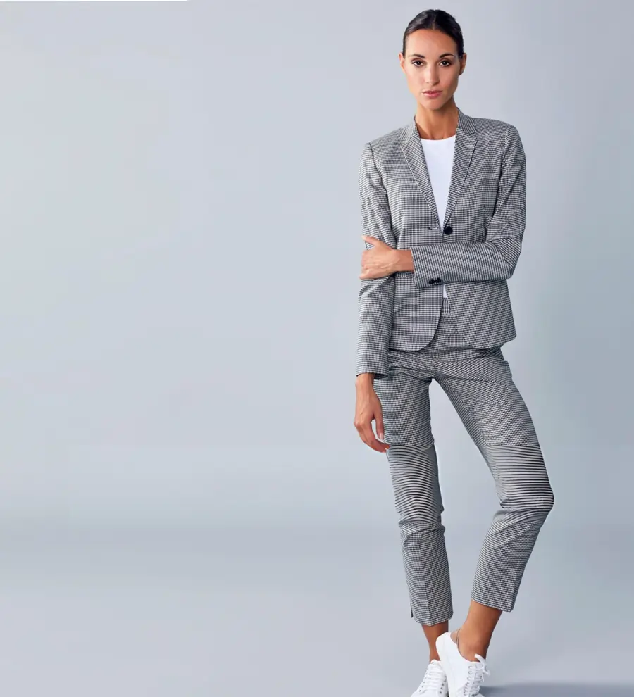 Professional woman in a grey checkered power suit and white sneakers for modern medical office wear.