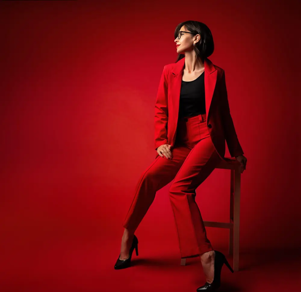 A woman styles a bold red blazer and matching trousers with black heels for a sophisticated festive event.