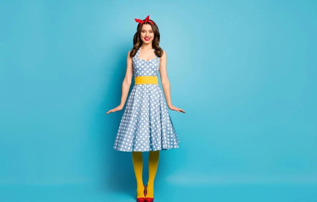 Woman wearing a blue polka dot swing dress with a red headband and yellow tights.