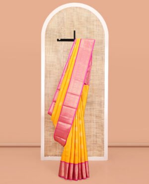 Yellow Vasundhara Silk Saree, Detailed With Zari Buttas And Stripes All Over Its Body, Complemented By A Contrast Border Of Rekku, Muthu, Poun, Chakram, And Mayil Designs, Grand Manga Design Pallu, And Paired With A Contrast Blouse