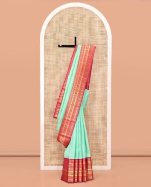 Turquoise Vasundhara Silk Saree, Embellished With Zari Buttas All Over Its Body, Complemented By A Contrast Border Of Thilakam Mokku, Yaanai, Iruthalai Pakshi, And Kodi Visiry Designs, Grand Pallu, And Paired With A Contrast Blouse