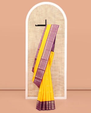 Yellow Vasundhara Silk Saree, Sparsely Woven With Zari Buttas All Over Its Body, Complemented By A Contrast Border Of Thilakam, Muthu, Mayil, And Mayil Kann Designs, Pallu Of Zari Designs, And Paired With A Contrast Blouse